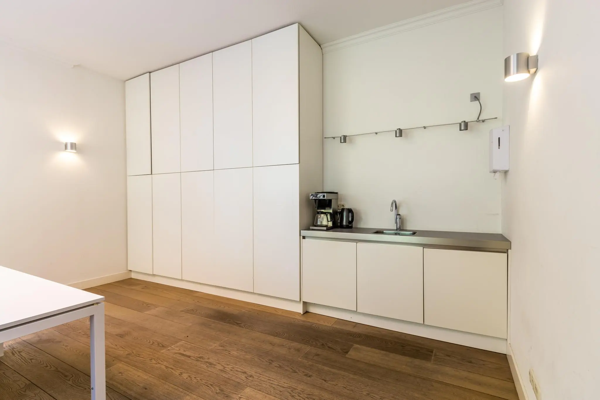 Moderne, minimalistische kitchenette met ingebouwde kasten en houten vloer aan de Langbroekerdijk A.